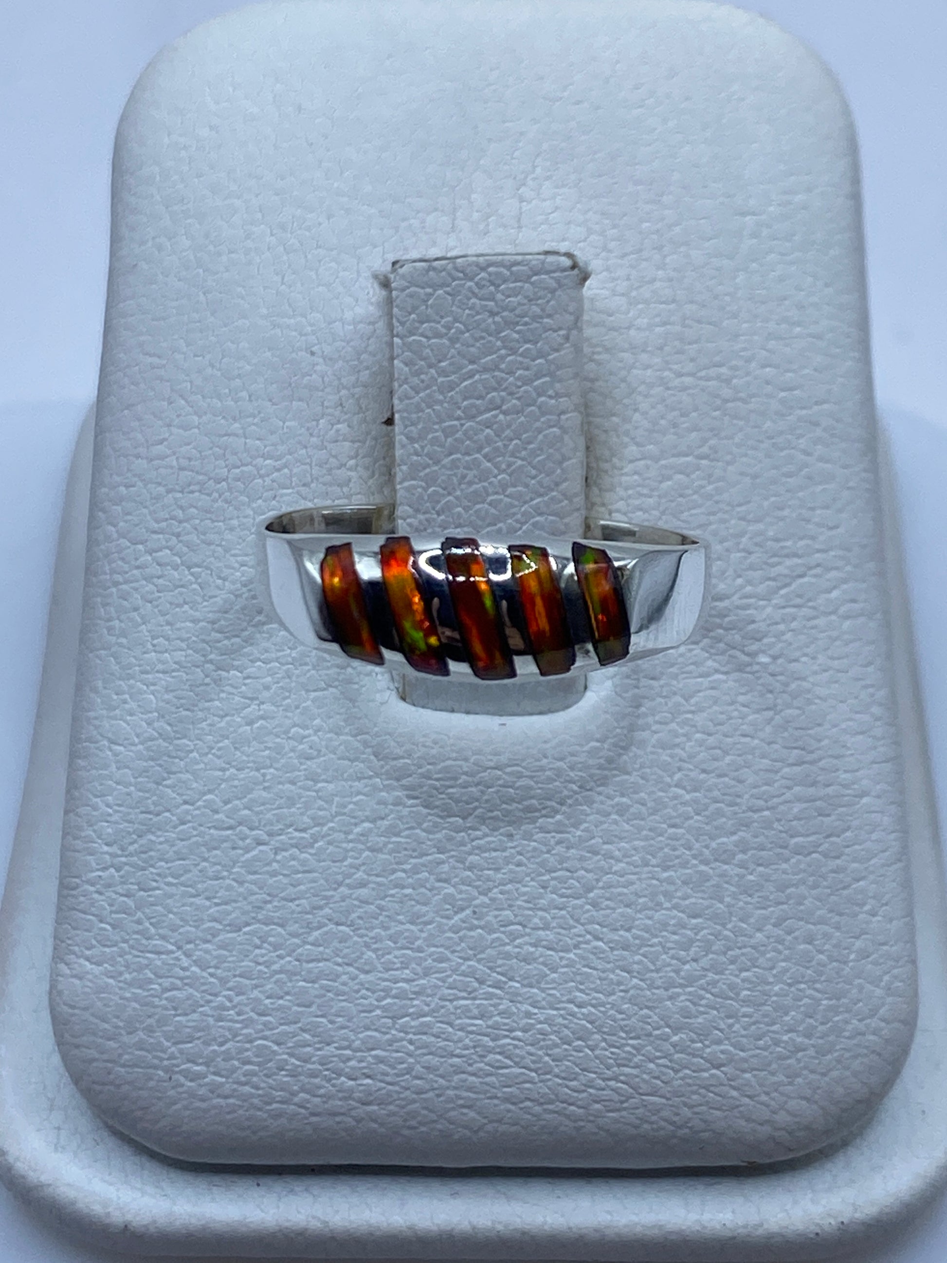 Anillo de plata solitario con ópalo de fuego natural mostrando fuego multicolor en la mano
