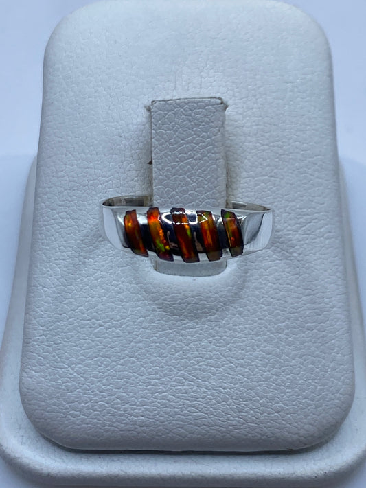 Anillo de plata solitario con ópalo de fuego natural mostrando fuego multicolor en la mano
