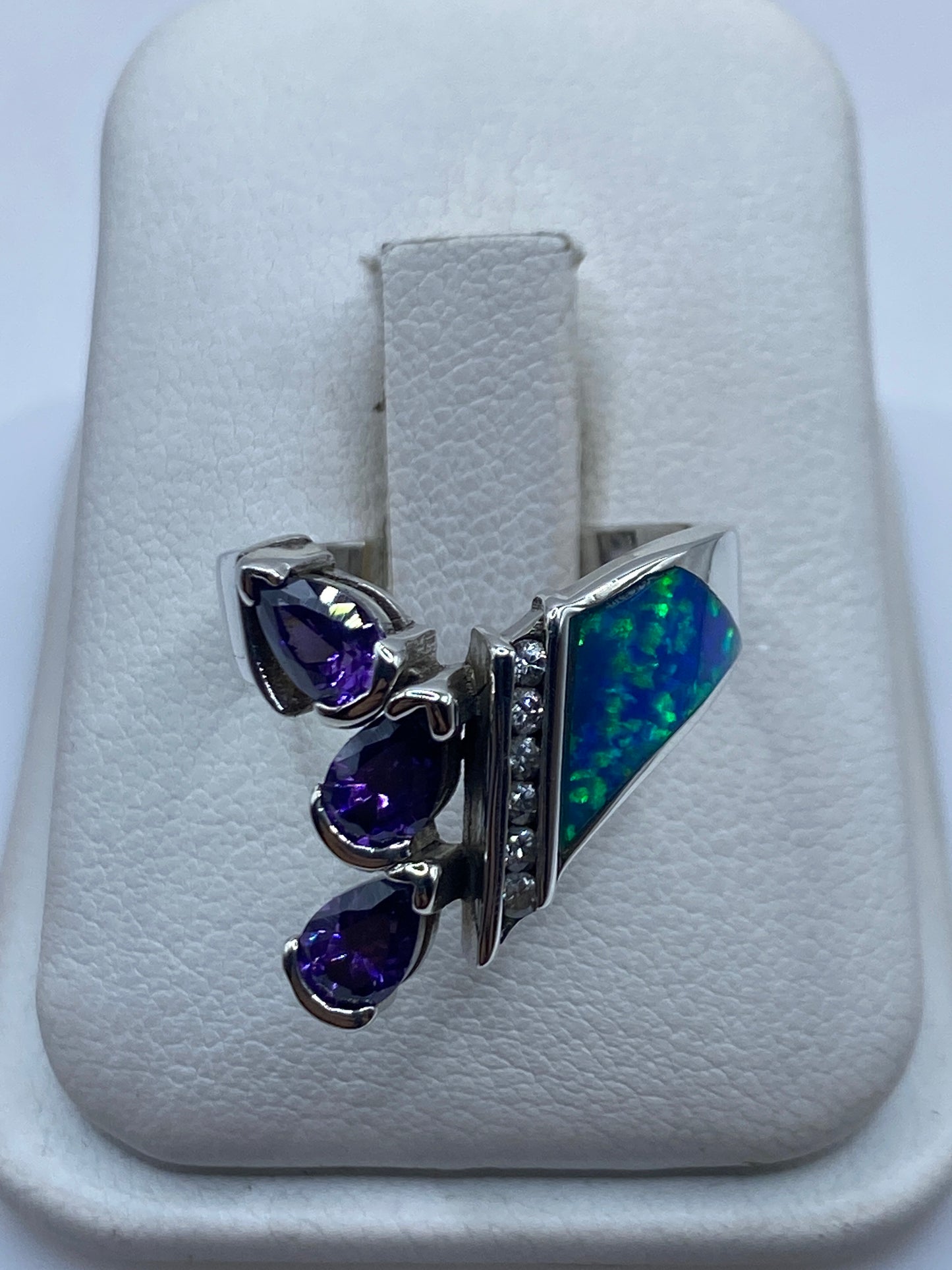 Anillo de plata con ópalo azul natural y circonias blancas escalonado en mano de mujer