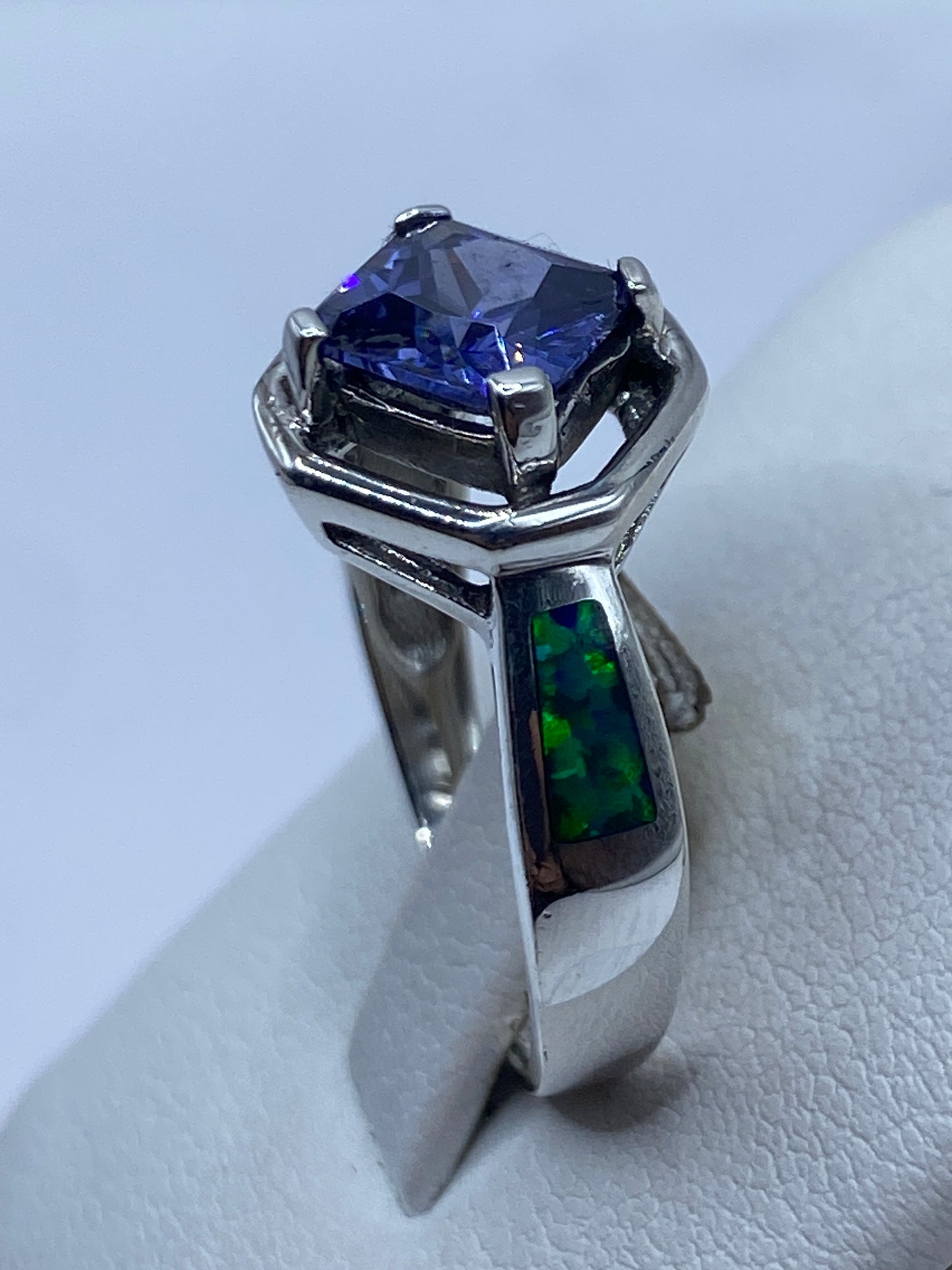 Anillo puesto en la mano de una mujer, ópalo azul brillando bajo la luz natural