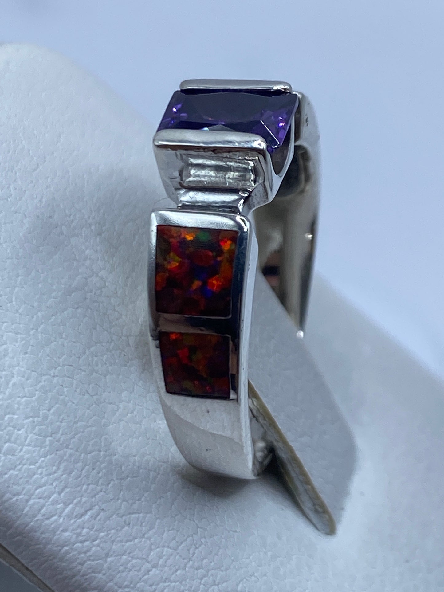 Anillo de ópalo de fuego multicolor en mano de mujer, mostrando juego de colores naturales