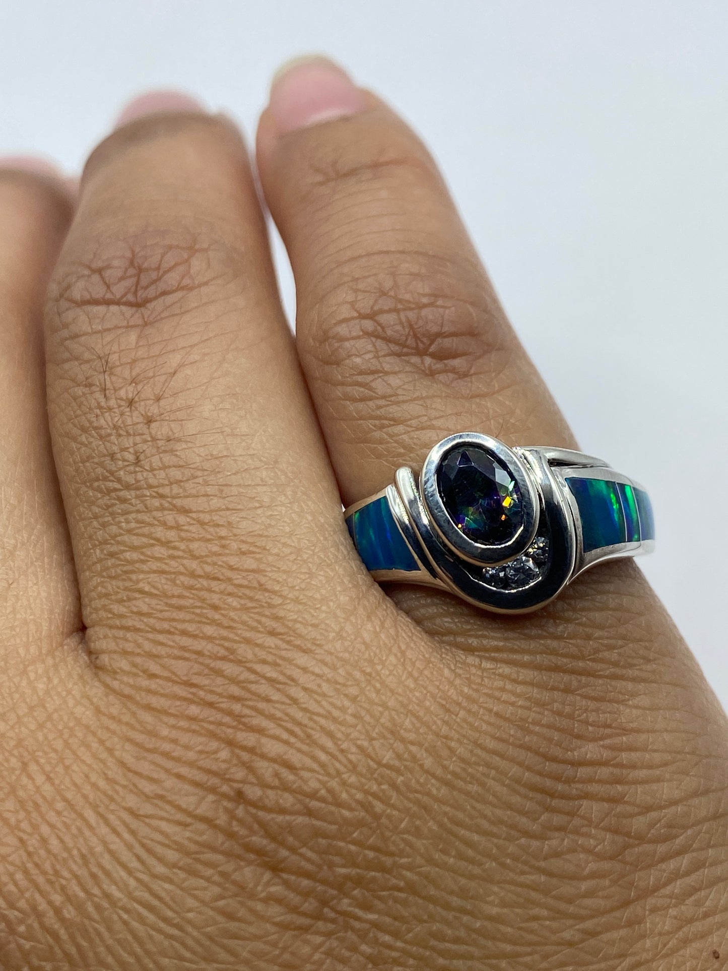Anillo en la mano mostrando el juego de color azul y verde del ópalo natural