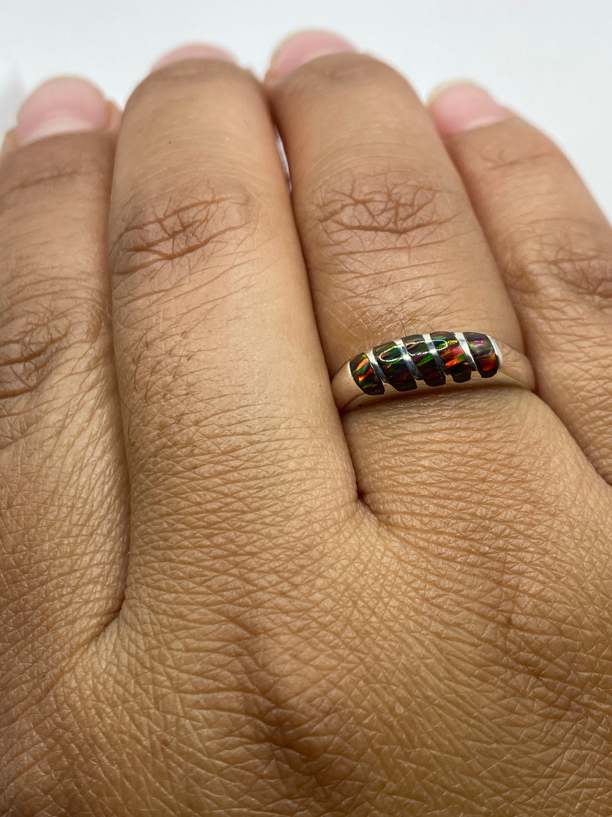Anillo en dedo mostrando el ópalo brillante y la banda pulida de plata pura