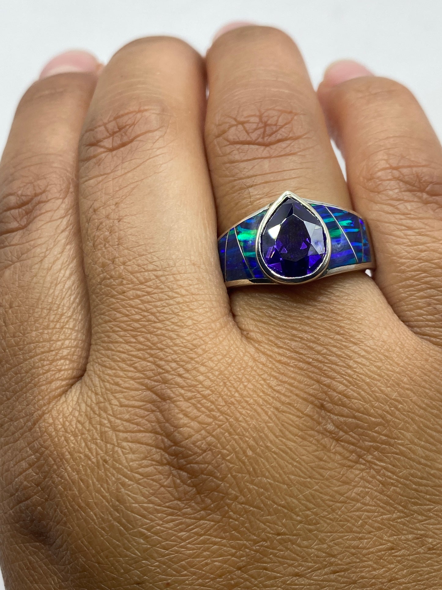 Anillo en la mano mostrando el sello 925 y el juego de luz del ópalo