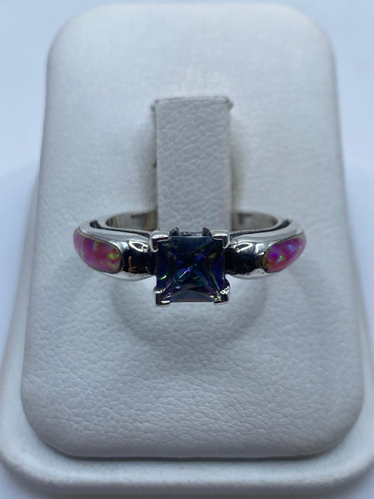 Anillo de plata coctel con ópalo de fuego rosa en mano de mujer mostrando juego de fuego multicolor