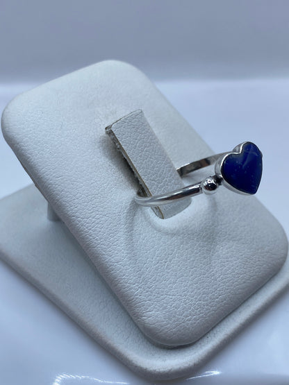 Anillo de plata con piedra azul oval en la mano de una mujer, mostrando el tamaño y brillo