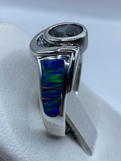 Anillo ópalo de fuego en la mano, con juego de colores azules y verdes bajo luz natural