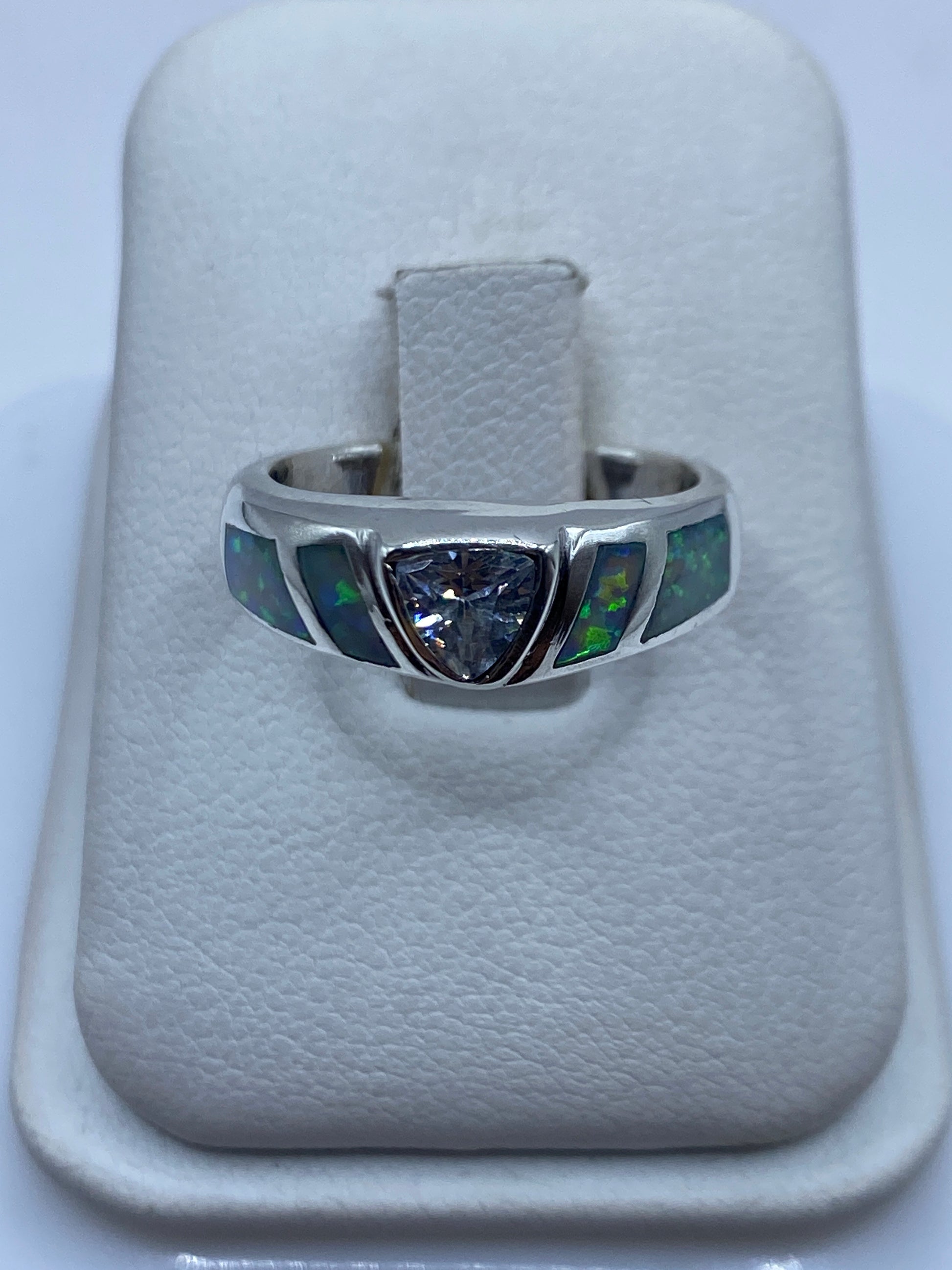 Anillo de plata banda ancha con ópalo de fuego natural mostrando destellos verdes en la mano