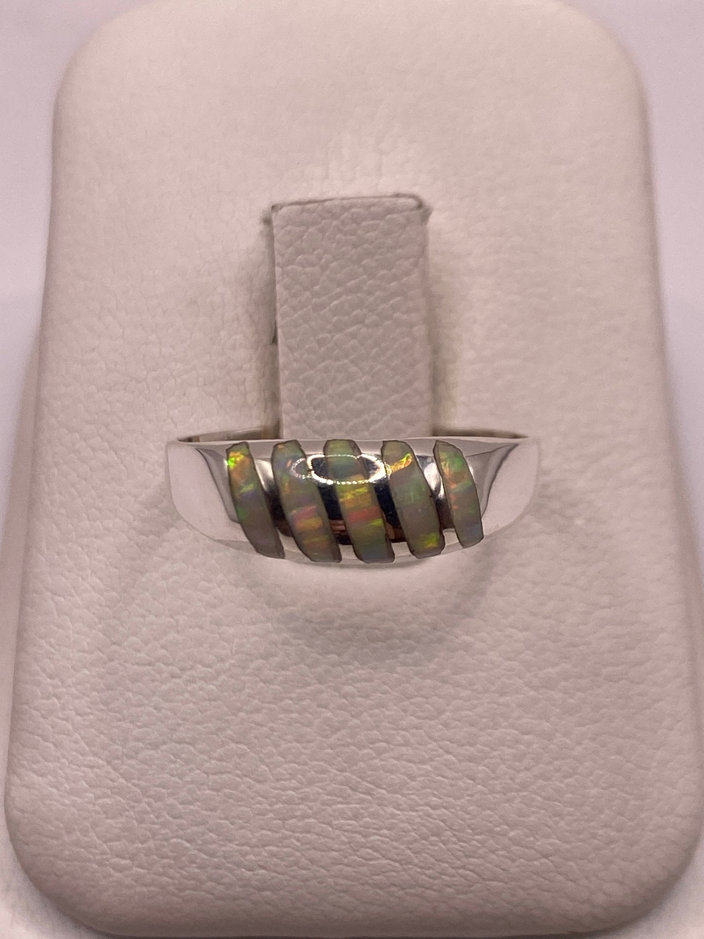 Anillo de plata minimalista con ópalo de fuego multicolor en la mano de un hombre