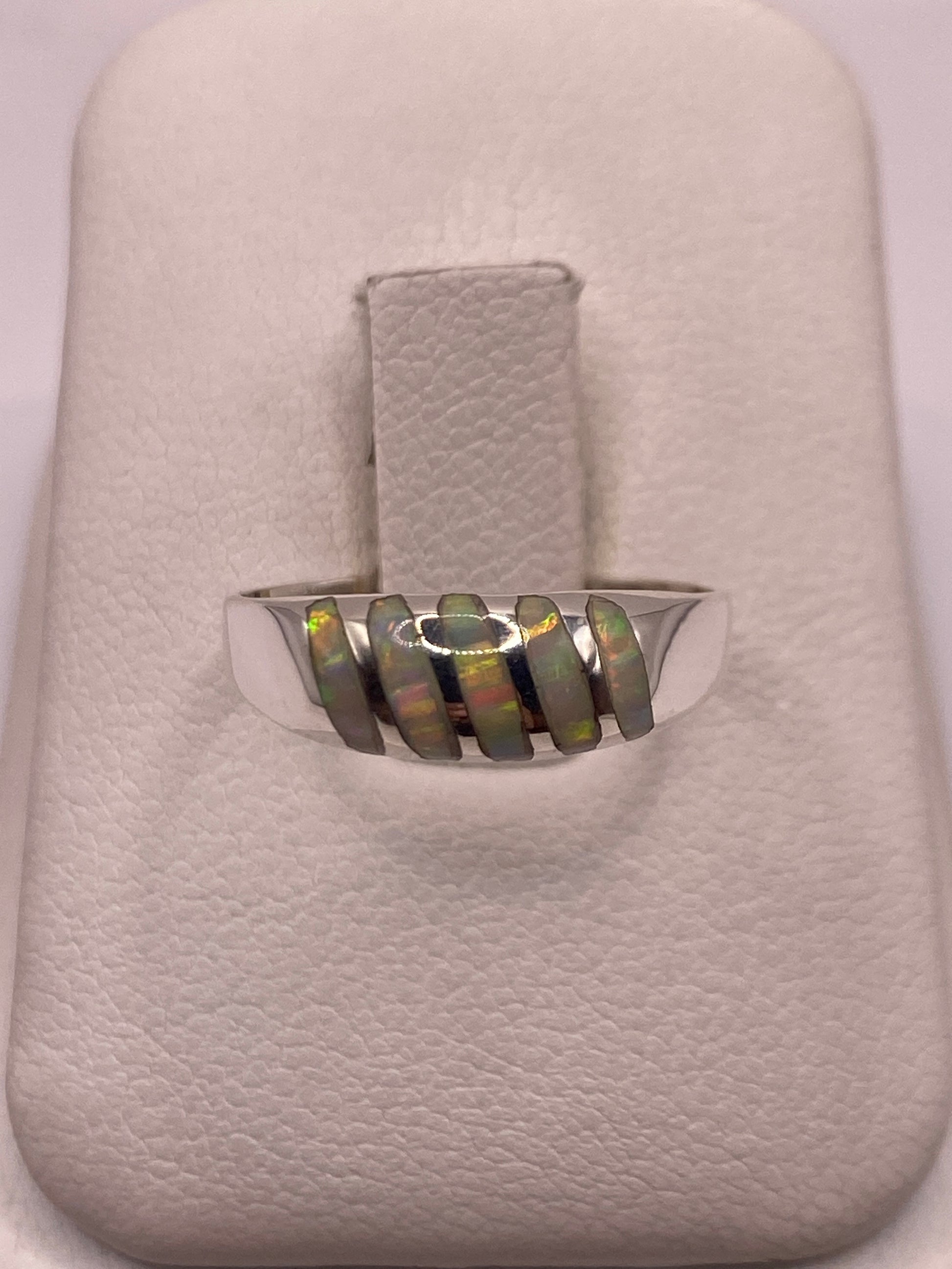 Anillo de plata minimalista con ópalo de fuego multicolor en la mano de un hombre