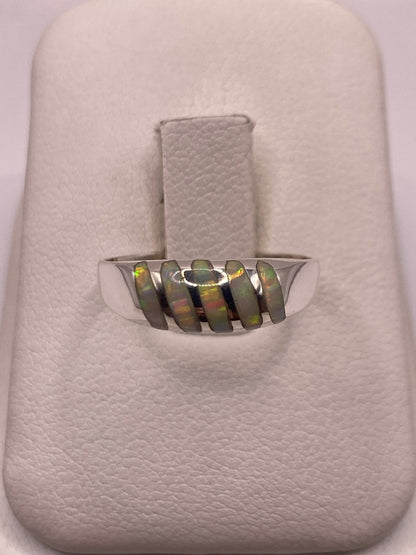 Anillo de plata minimalista con ópalo de fuego multicolor en la mano de un hombre