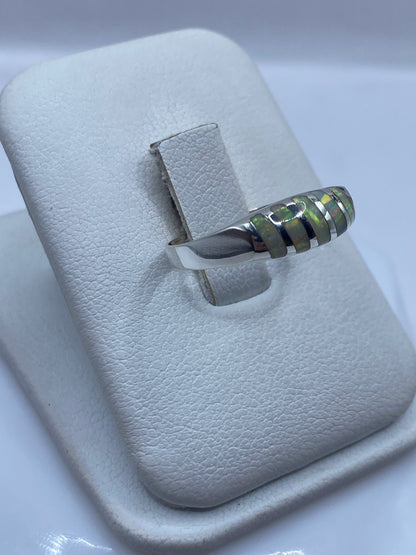 Vista lateral del anillo minimalista de plata con ópalo de fuego reflejando luz