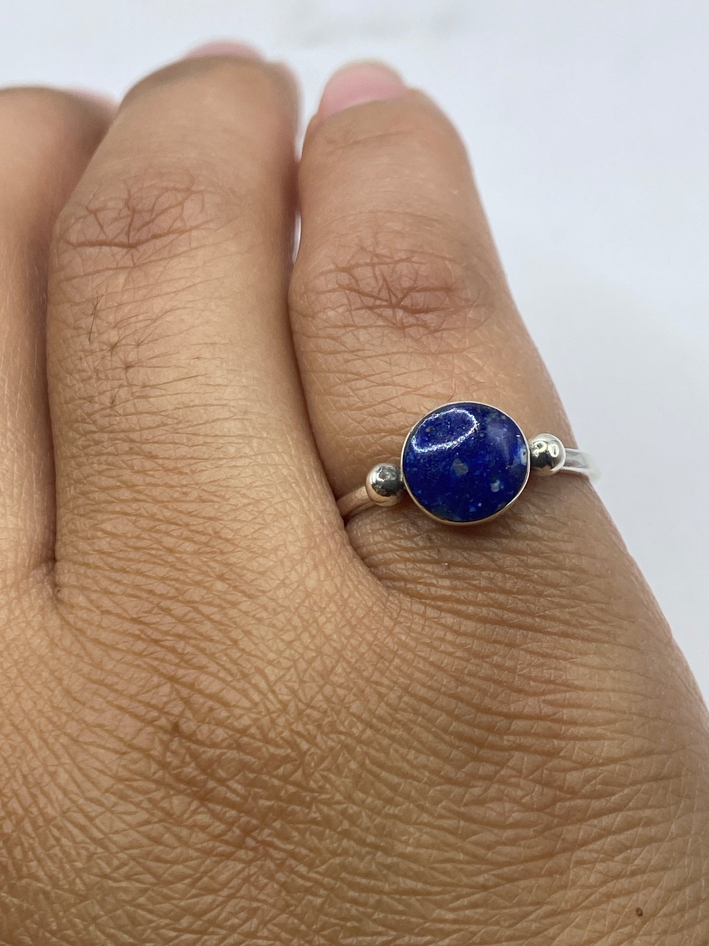 Anillo solitario sobre dedo mostrando el color profundo del lapislázuli y pulido de la plata
