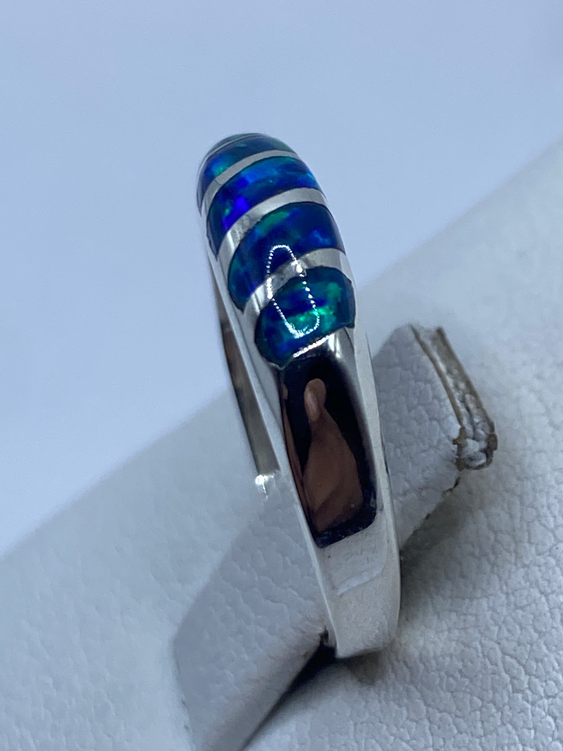 Anillo de ópalo azul puesto en dedo, mostrando los juegos de luz