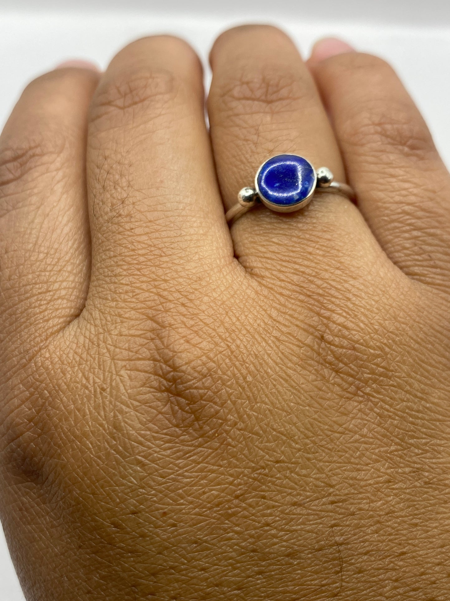 Anillo de plata con lapislázuli en la mano de una mujer sobre fondo neutro