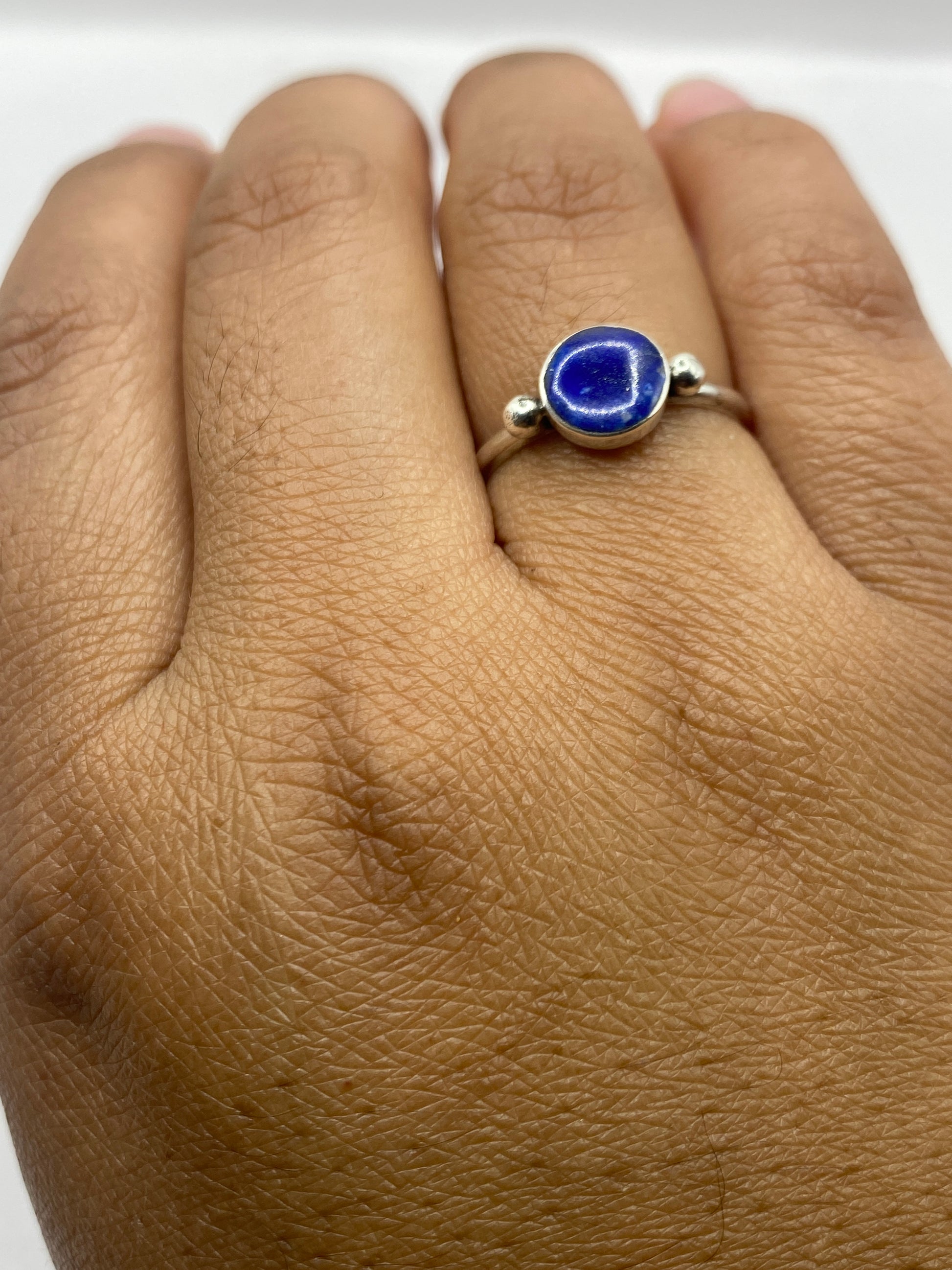 Anillo de plata con lapislázuli en la mano de una mujer sobre fondo neutro