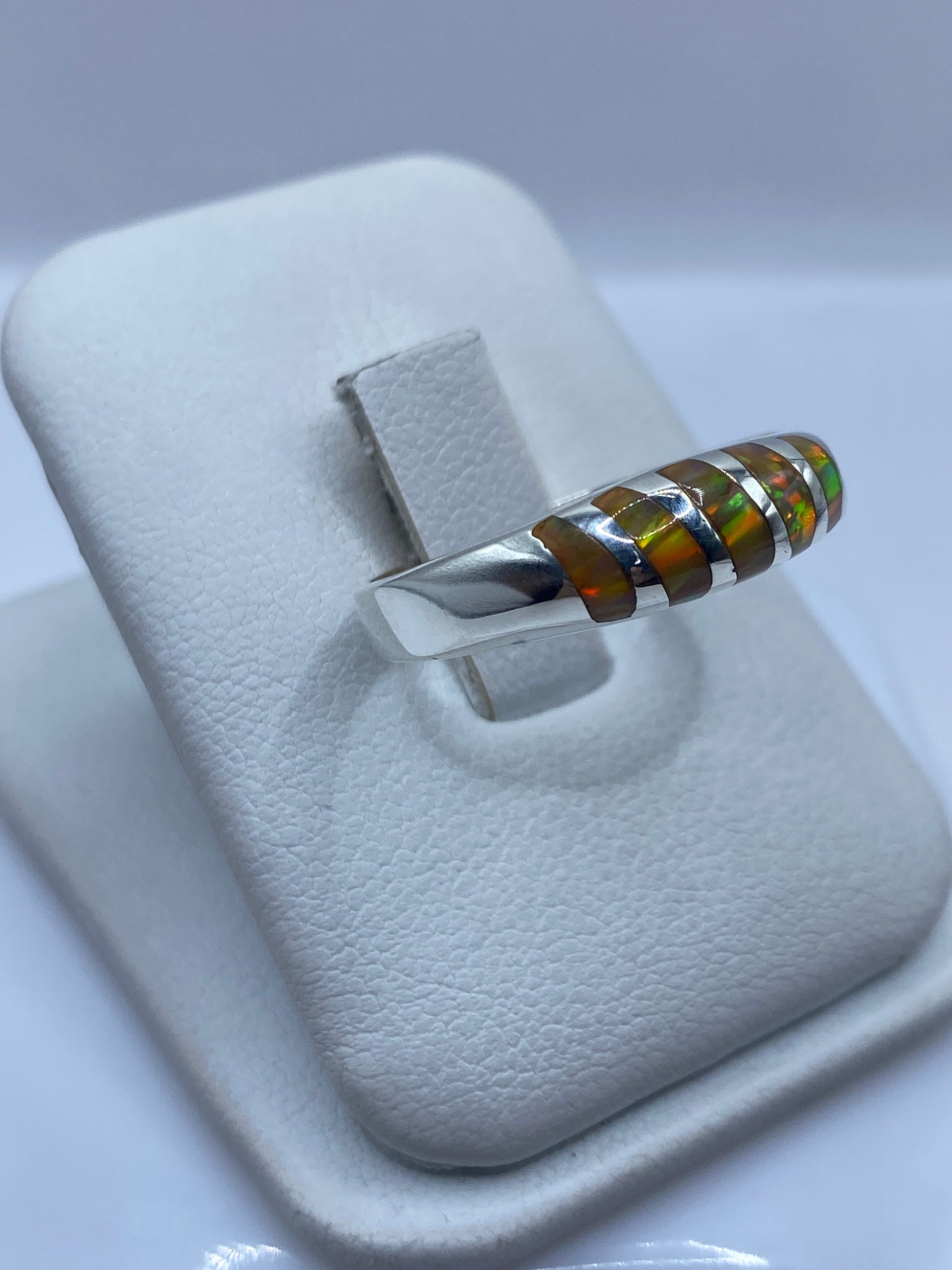 Detalle lateral del anillo mostrando el engaste del ópalo y el fuego amarillo-naranja