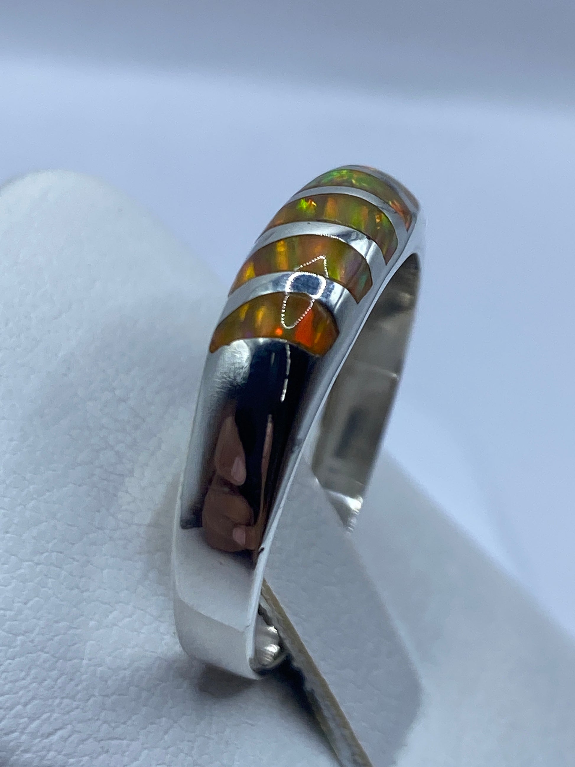 Anillo ópalo de fuego en la mano mostrando los tonos amarillo, naranja y verde de la piedra