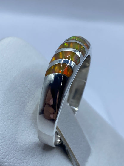 Anillo ópalo de fuego en la mano mostrando los tonos amarillo, naranja y verde de la piedra
