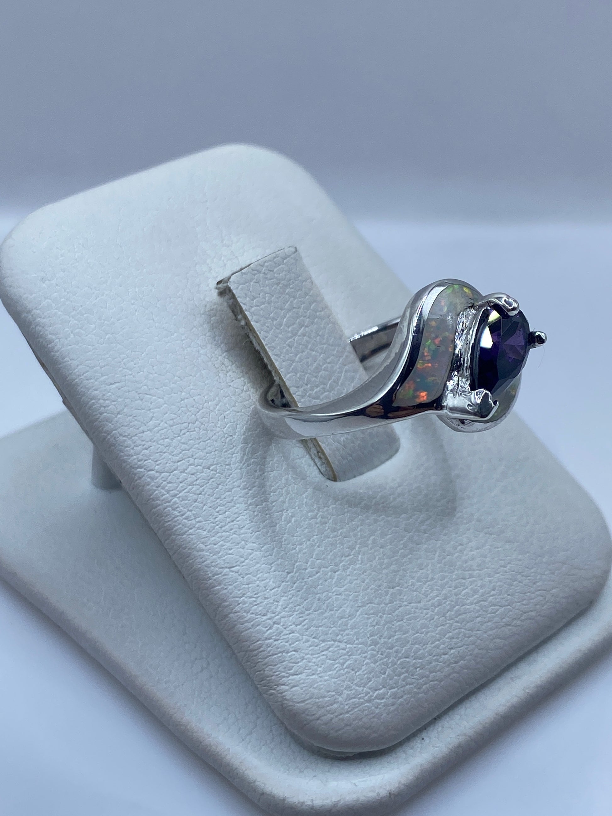 Anillo ópalo de fuego en la mano de una mujer, luz reflejando los colores naturales