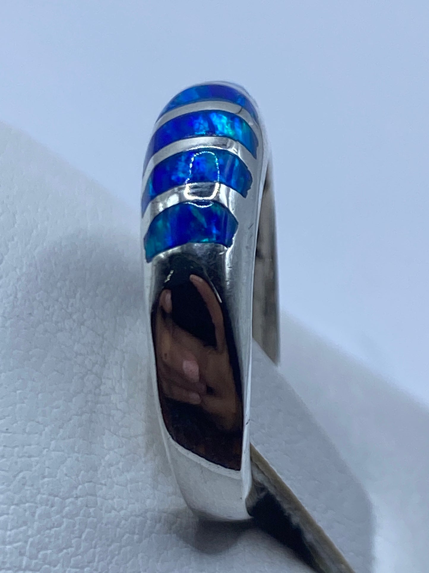 Anillo de ópalo azul visto desde el lado, evidenciando la banda de plata escalonada