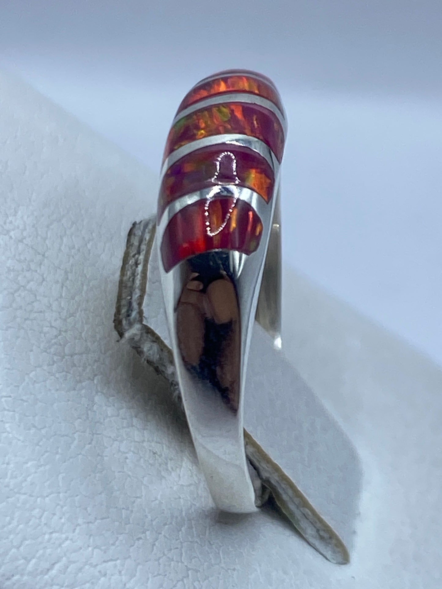 Detalle del engaste del ópalo natural en plata, mostrando refracción de luz rosa y fuego
