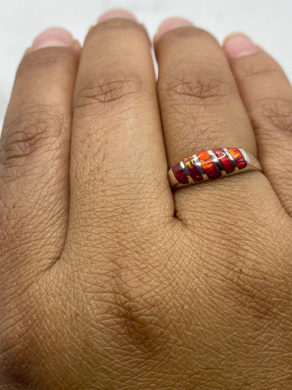 Anillo ópalo fuego rosa en dedo de mujer, destacando el brillo natural de la piedra