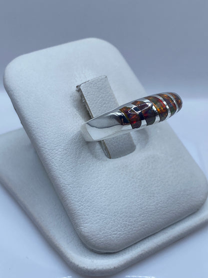 Vista lateral del anillo moderno con banda de plata y ópalo de fuego en juego de colores