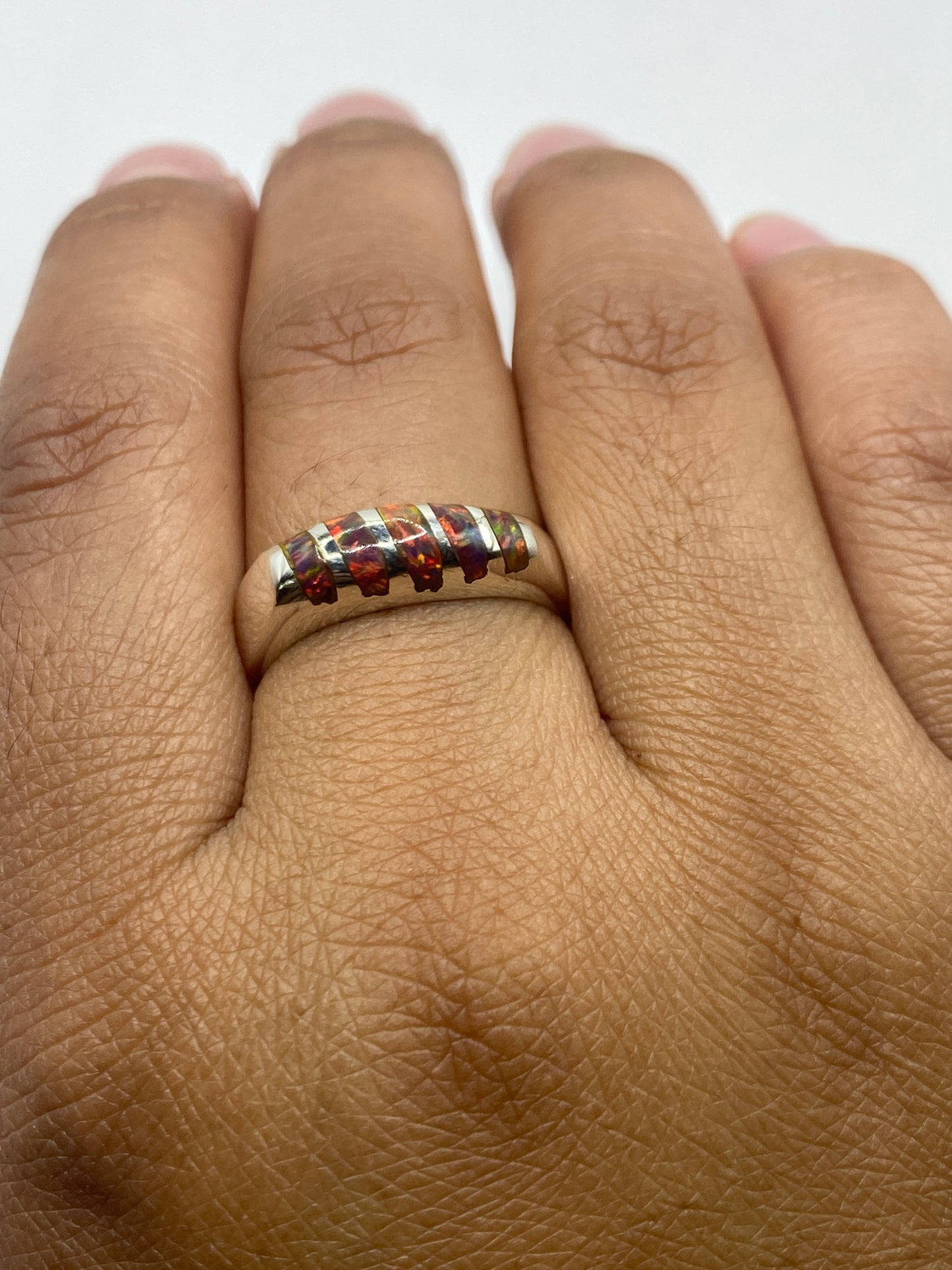 Anillo puesto en dedo mostrando el ópalo natural y la banda de plata .950 pulida