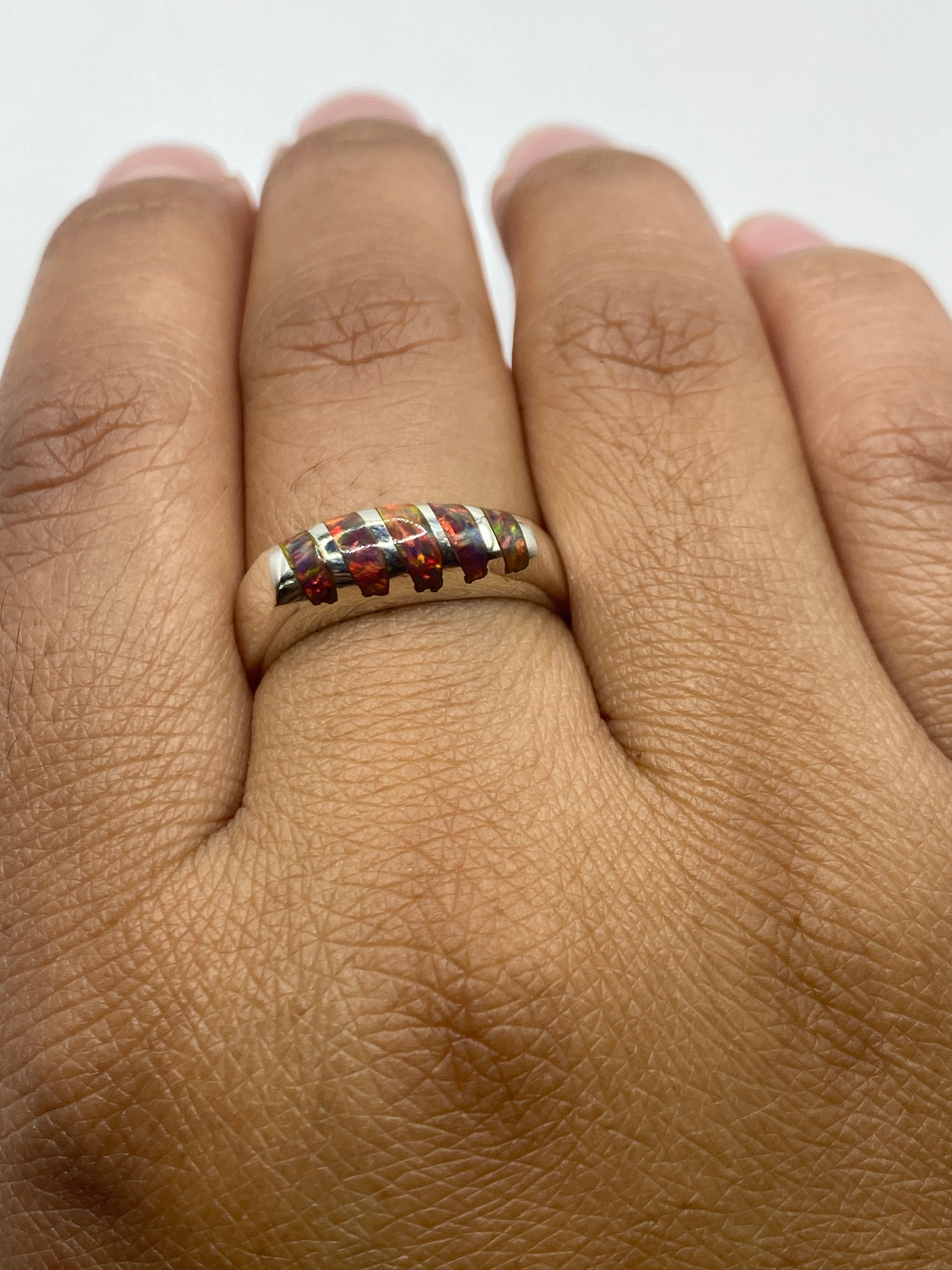 Anillo puesto en dedo mostrando el ópalo natural y la banda de plata .950 pulida