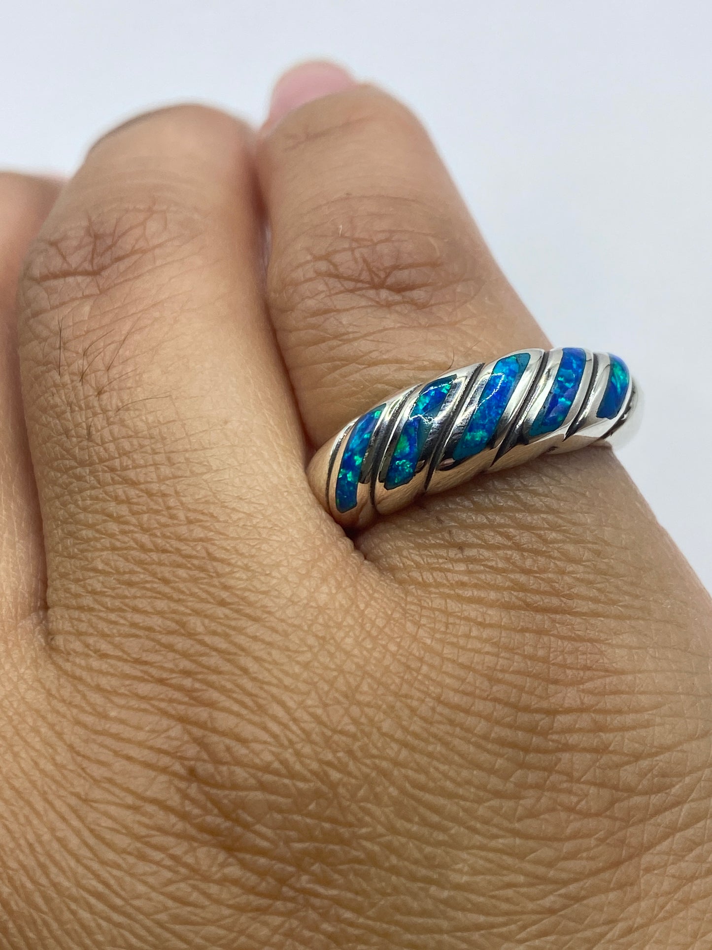 Anillo torcido sobre fondo gris mostrando sello 950 y brillo de la plata pura