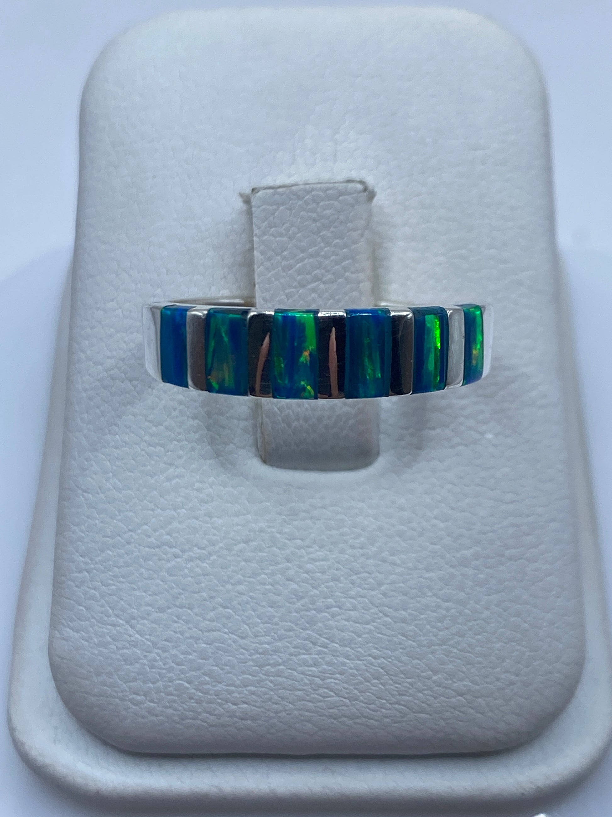 Anillo de plata con banda alternada de ópalo de fuego azul y verde en dedo de mujer