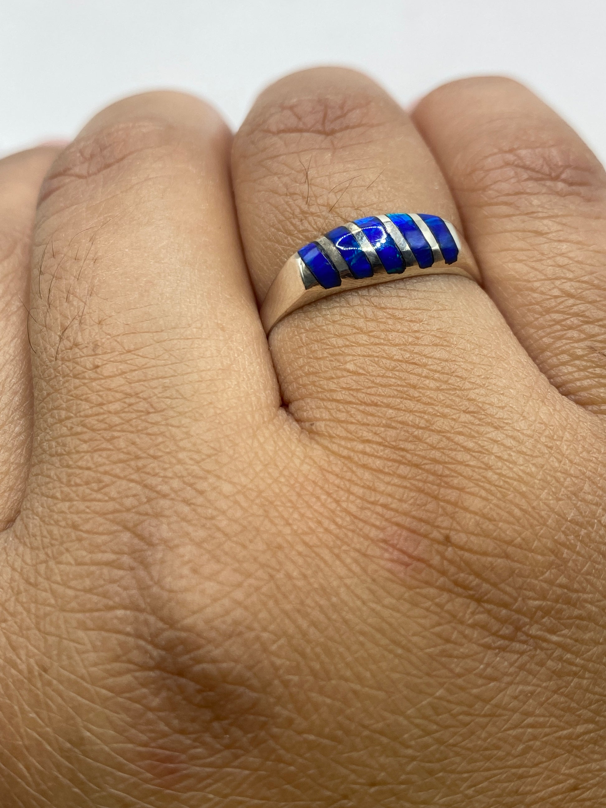 Anillo de ópalo de fuego azul en la mano mostrando el fuego y la ligereza del diseño