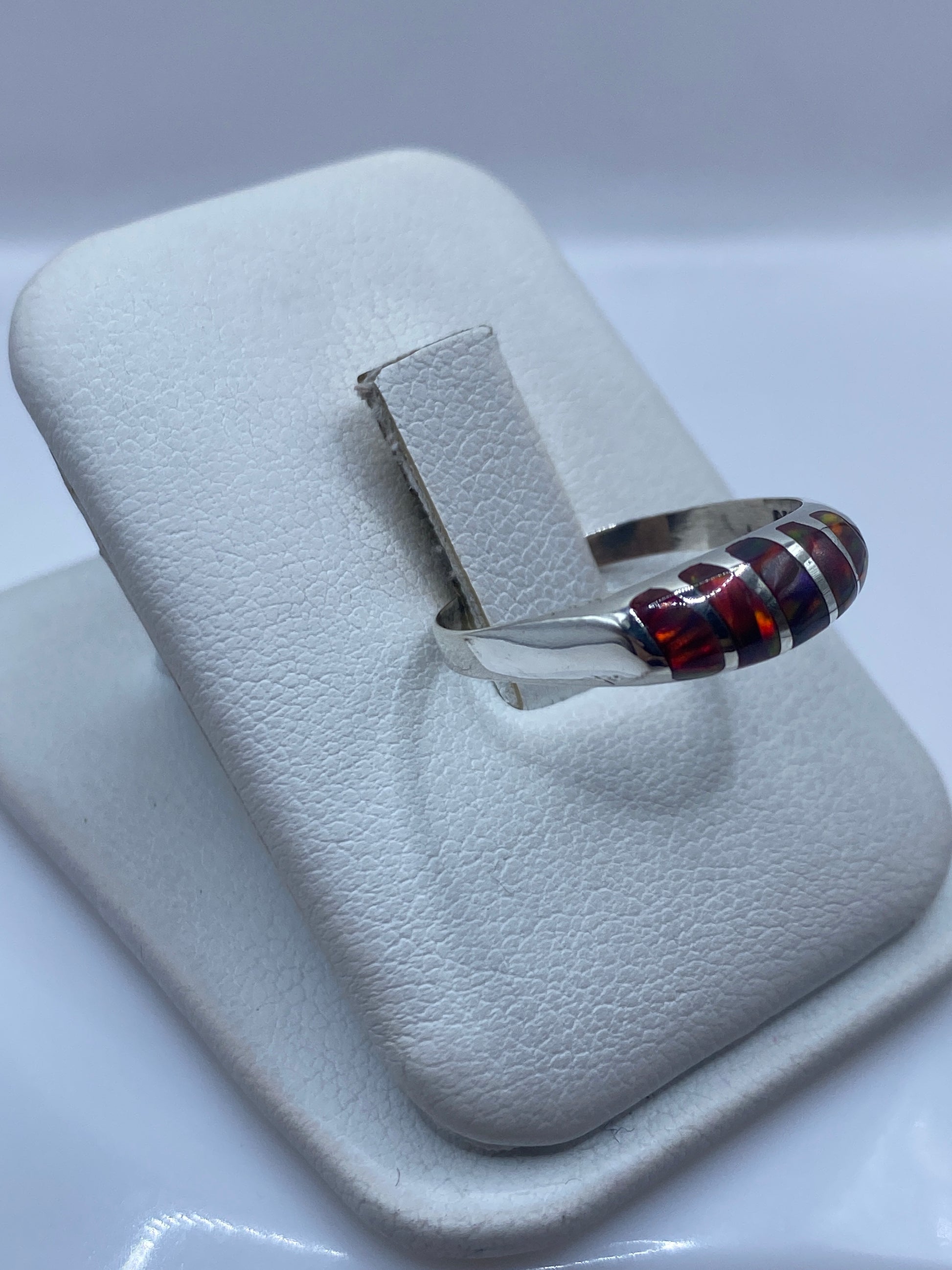 Detalle lateral del anillo mostrando el juego de colores rojo, naranja y azul del ópalo