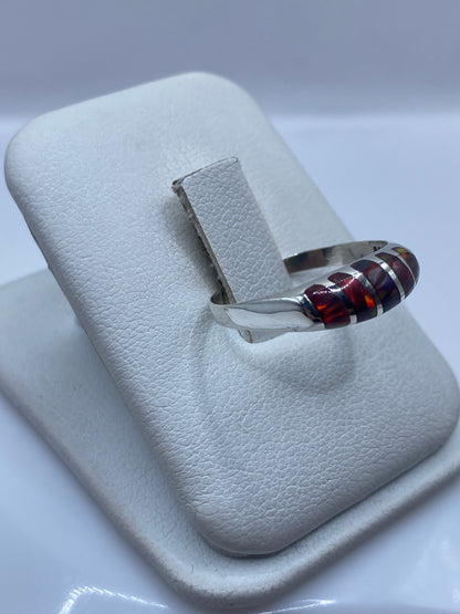 Detalle lateral del anillo mostrando el juego de colores rojo, naranja y azul del ópalo