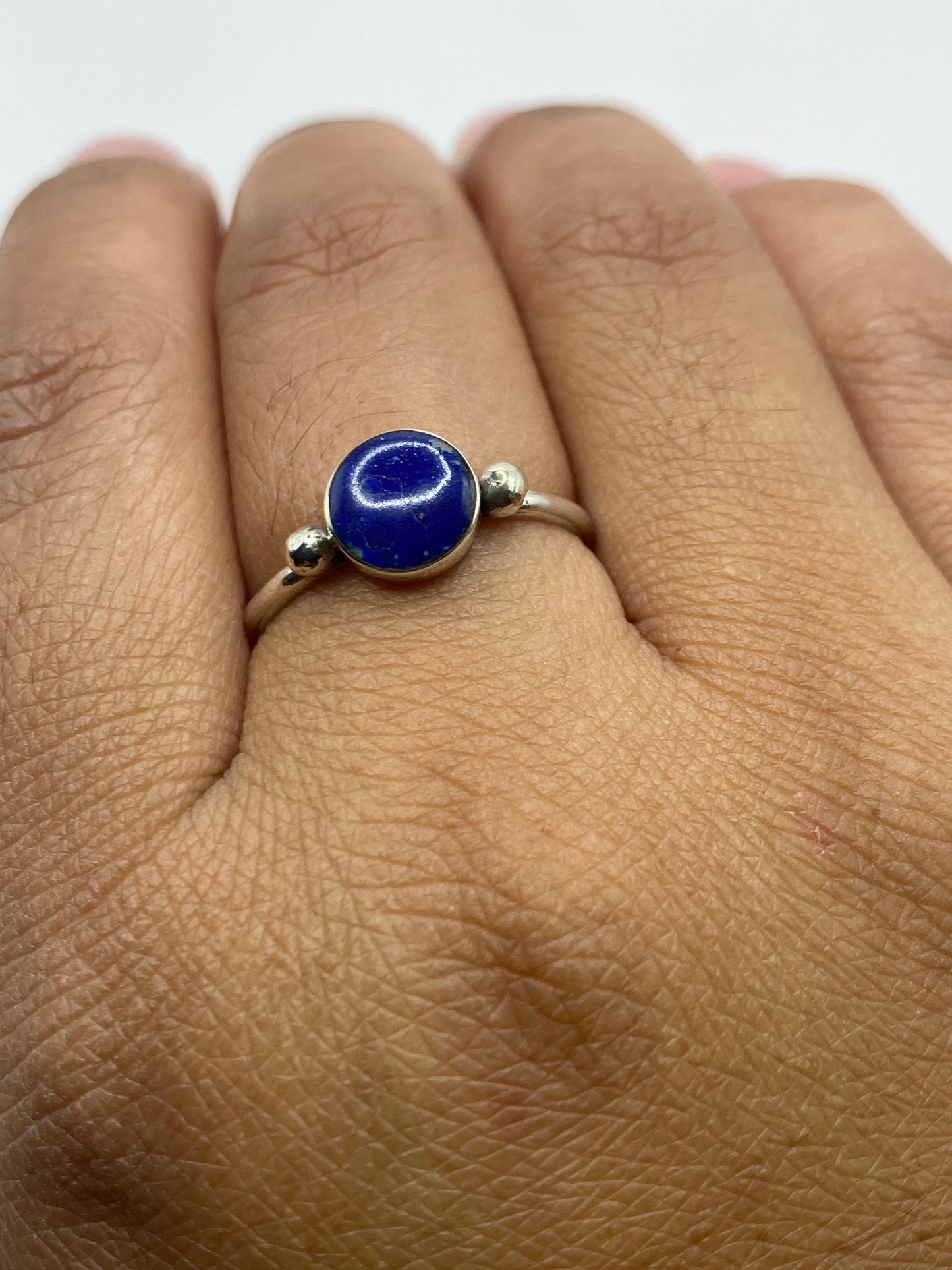 Anillo de plata con lapislázuli puesto en dedo, luz natural