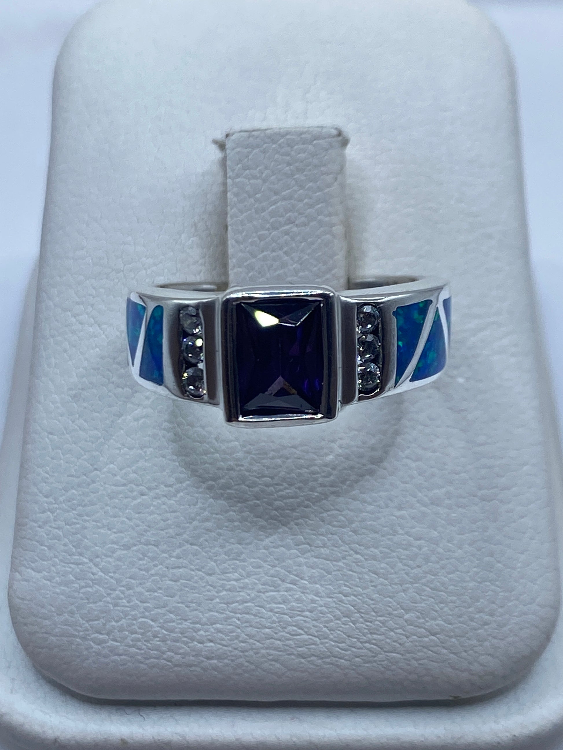 Anillo de plata con ópalo de fuego azul y piedras negras, vista frontal en estuche blanco