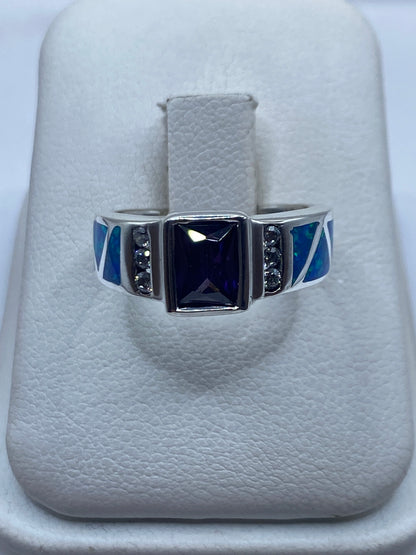 Anillo de plata con ópalo de fuego azul y piedras negras, vista frontal en estuche blanco