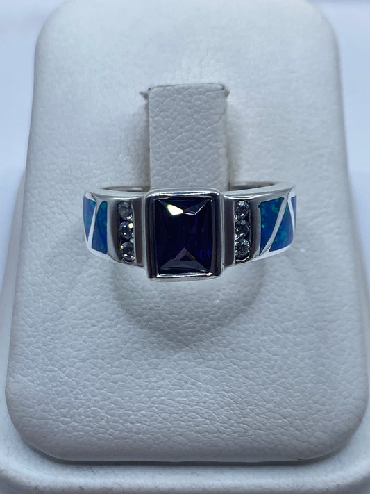 Anillo de plata con ópalo de fuego azul y piedras negras, vista frontal en estuche blanco
