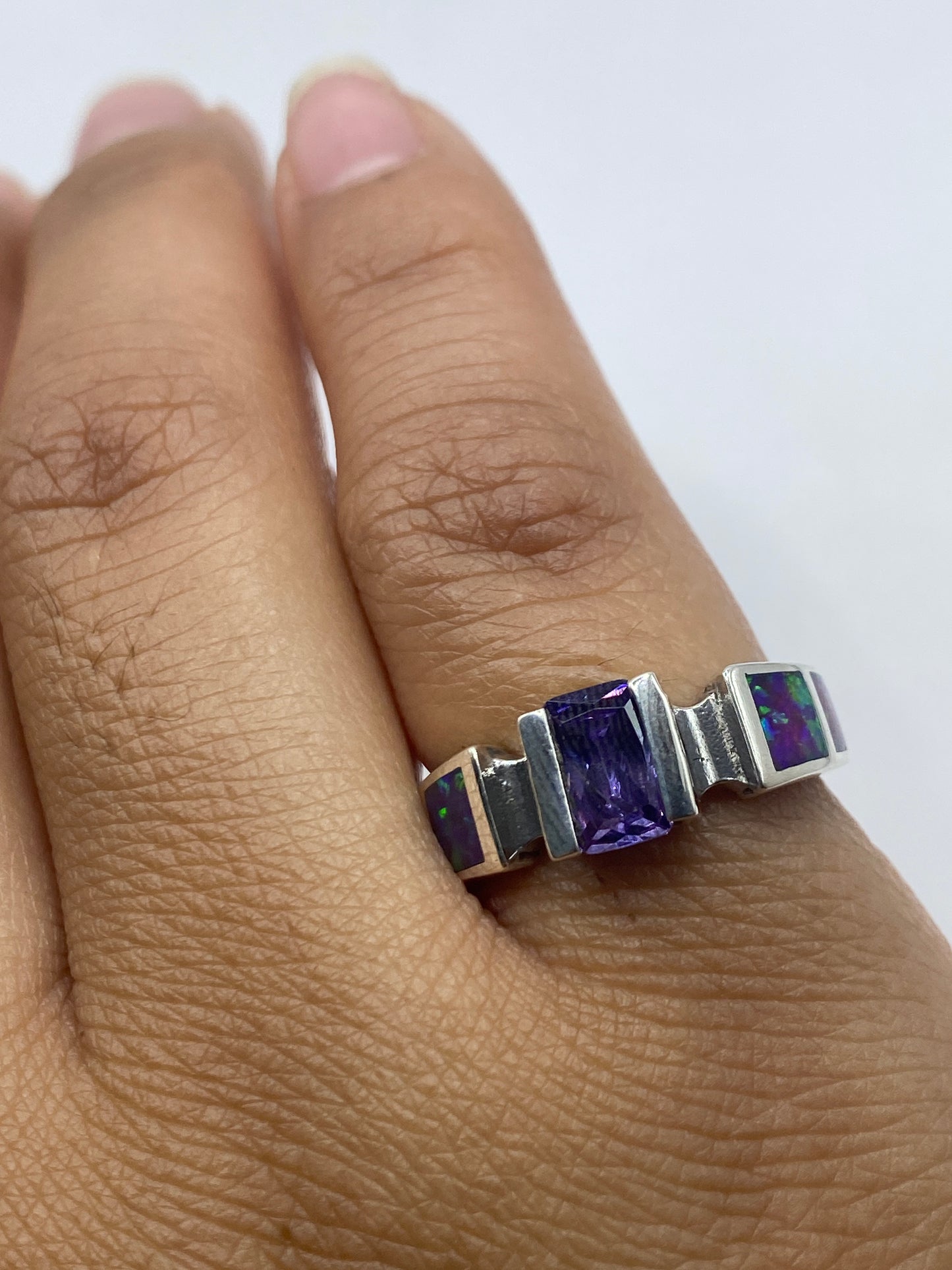 Anillo en dedo con ópalo de fuego brillando en tonos dorados, verdes y púrpuras