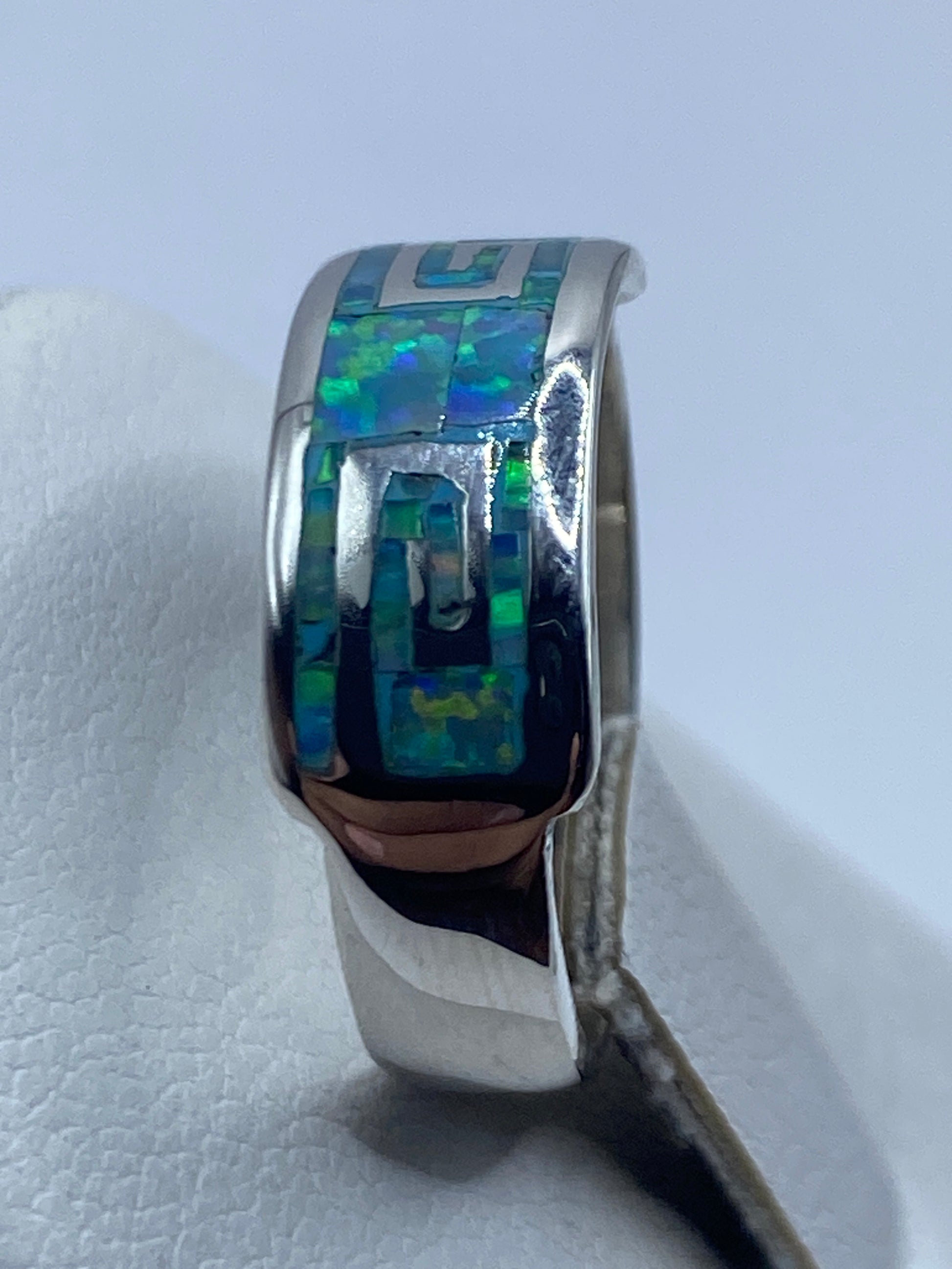 Anillo geométrico en la mano mostrando el juego cromático del ópalo natural