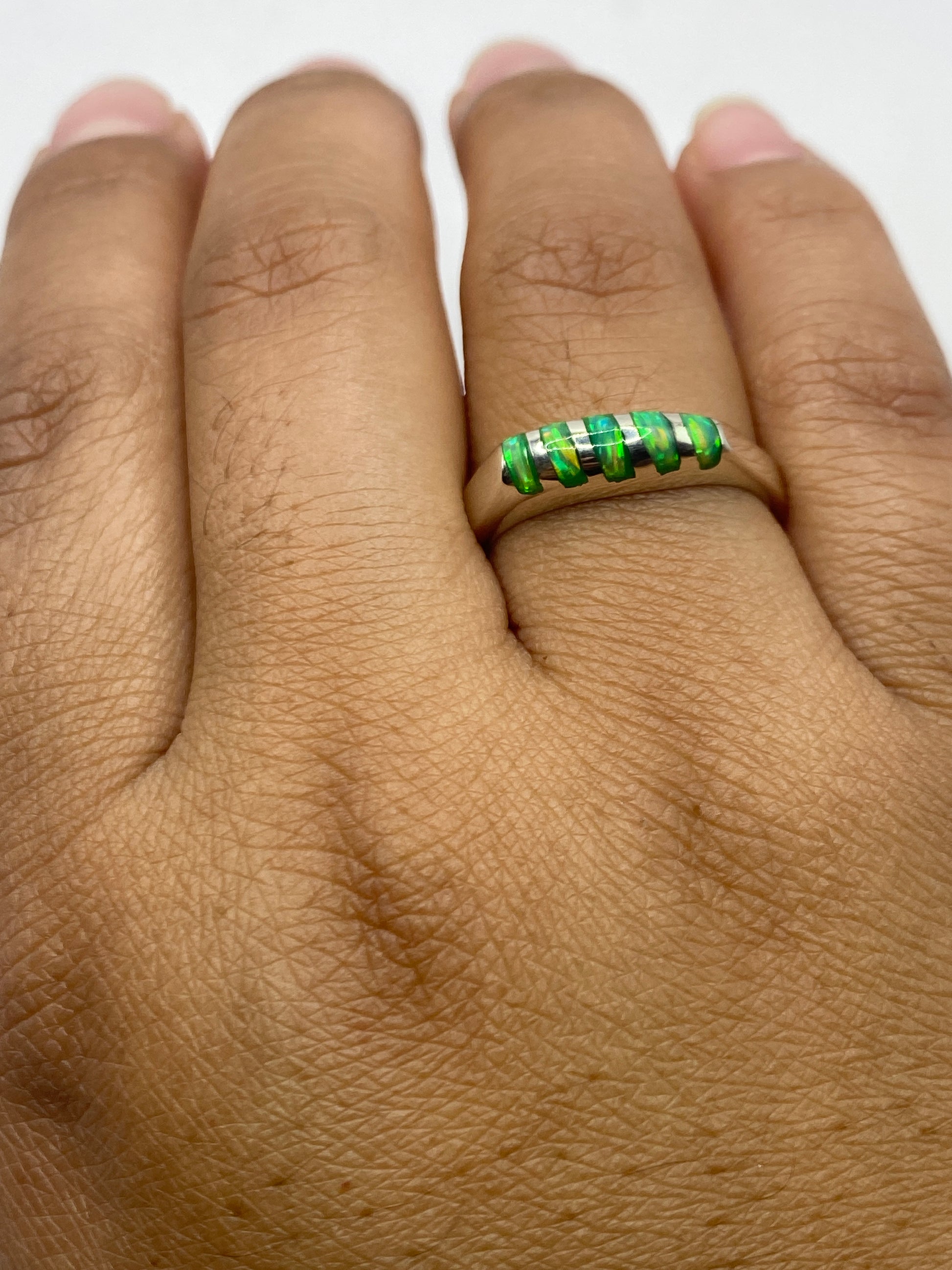 Anillo sobre fondo neutro exhibiendo el brillo y fuego del ópalo verde limón