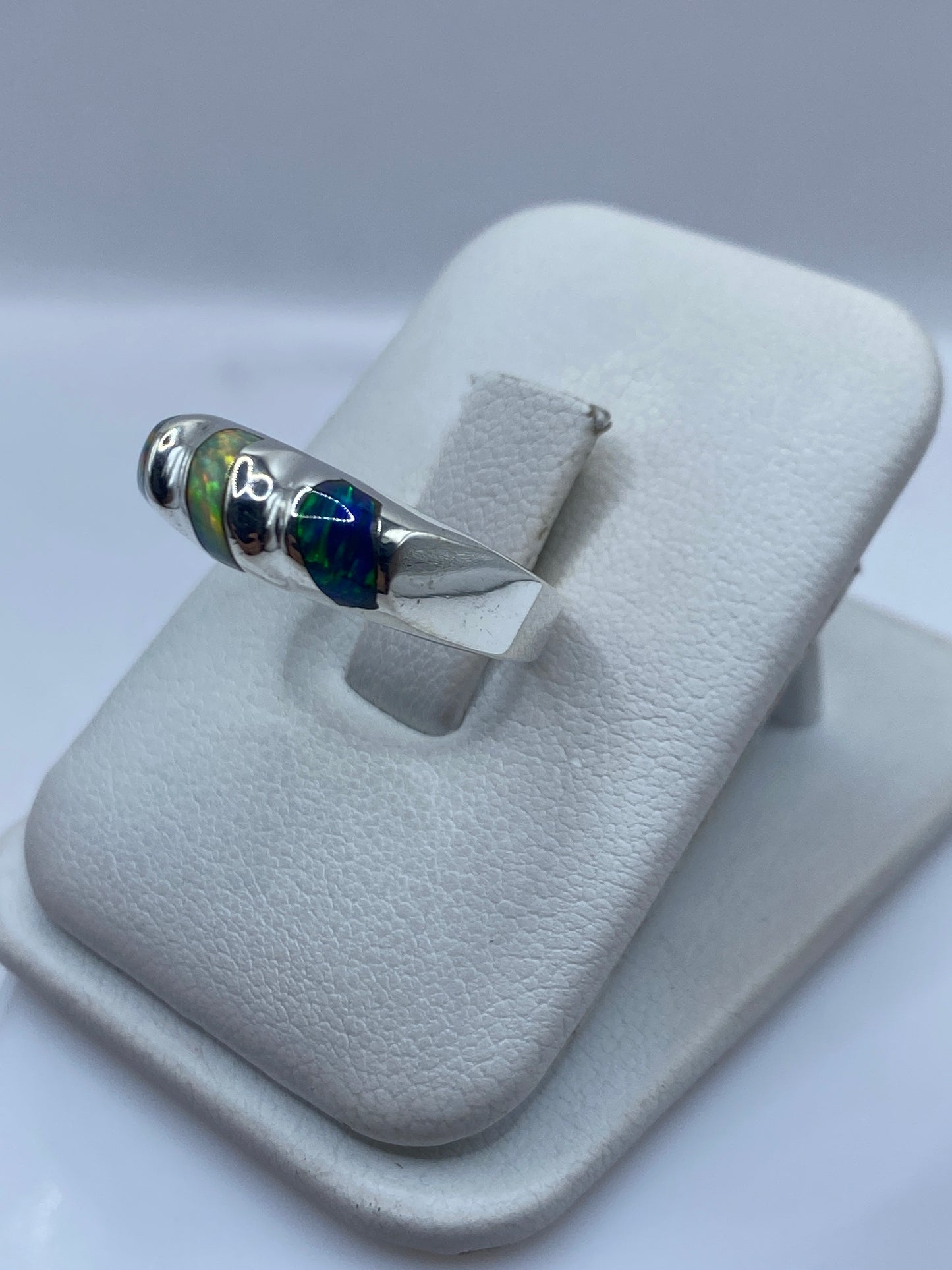 Detalle frontal del anillo mostrando juego de colores del ópalo: verde, azul y amarillo