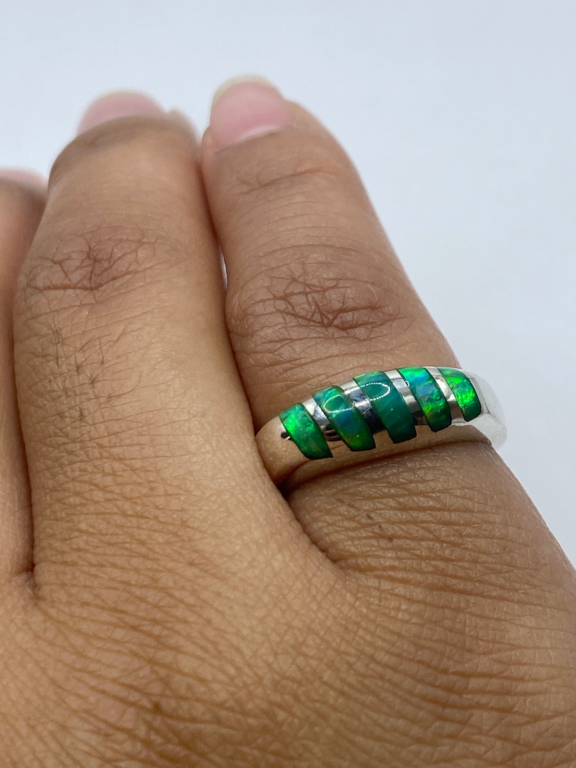 Anillo de ópalo de fuego sobre fondo gris mostrando el juego de luz en la piedra