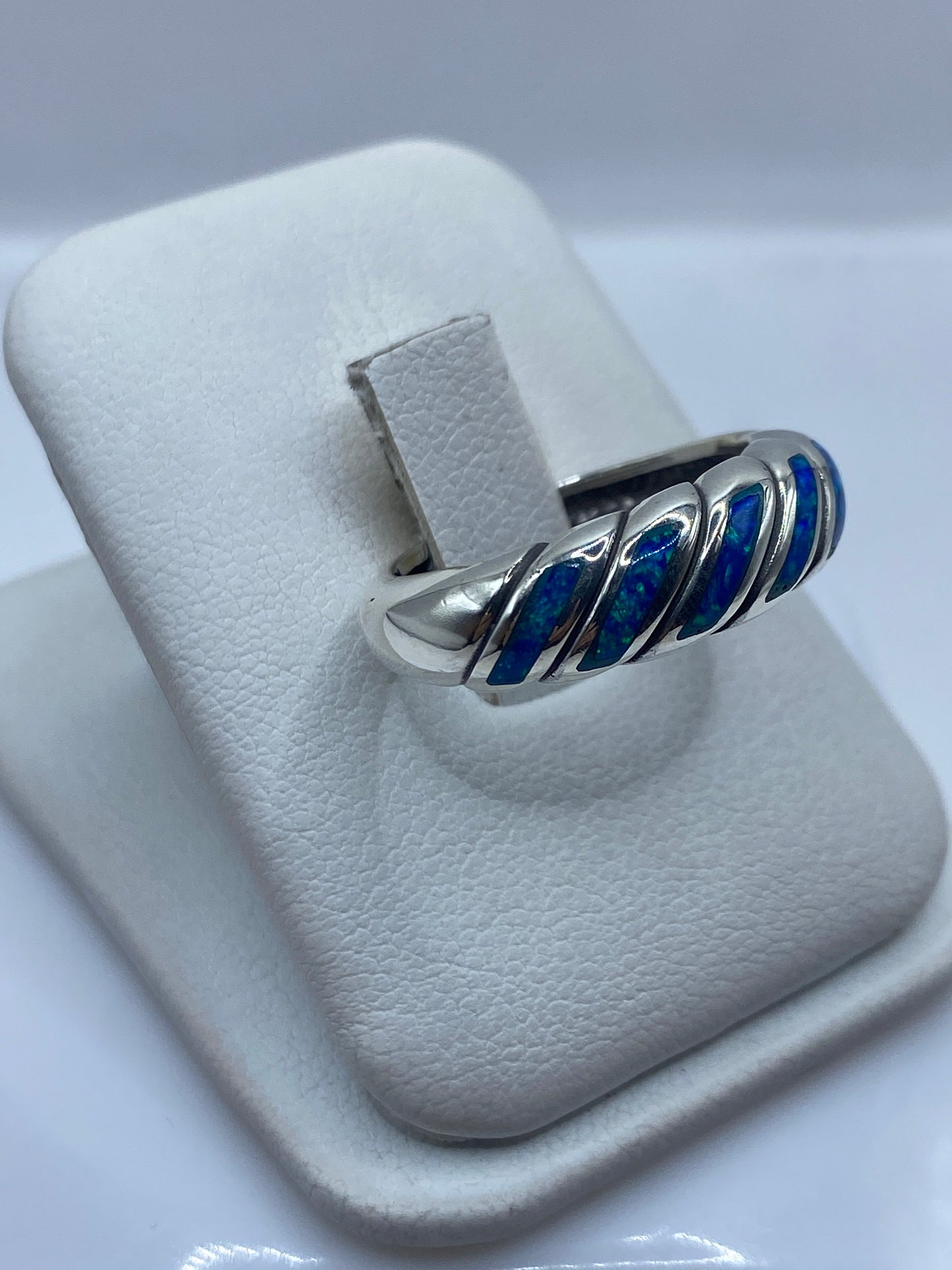 Anillo torsionado en plata con ópalo de fuego mostrando juego de luz azul-verde