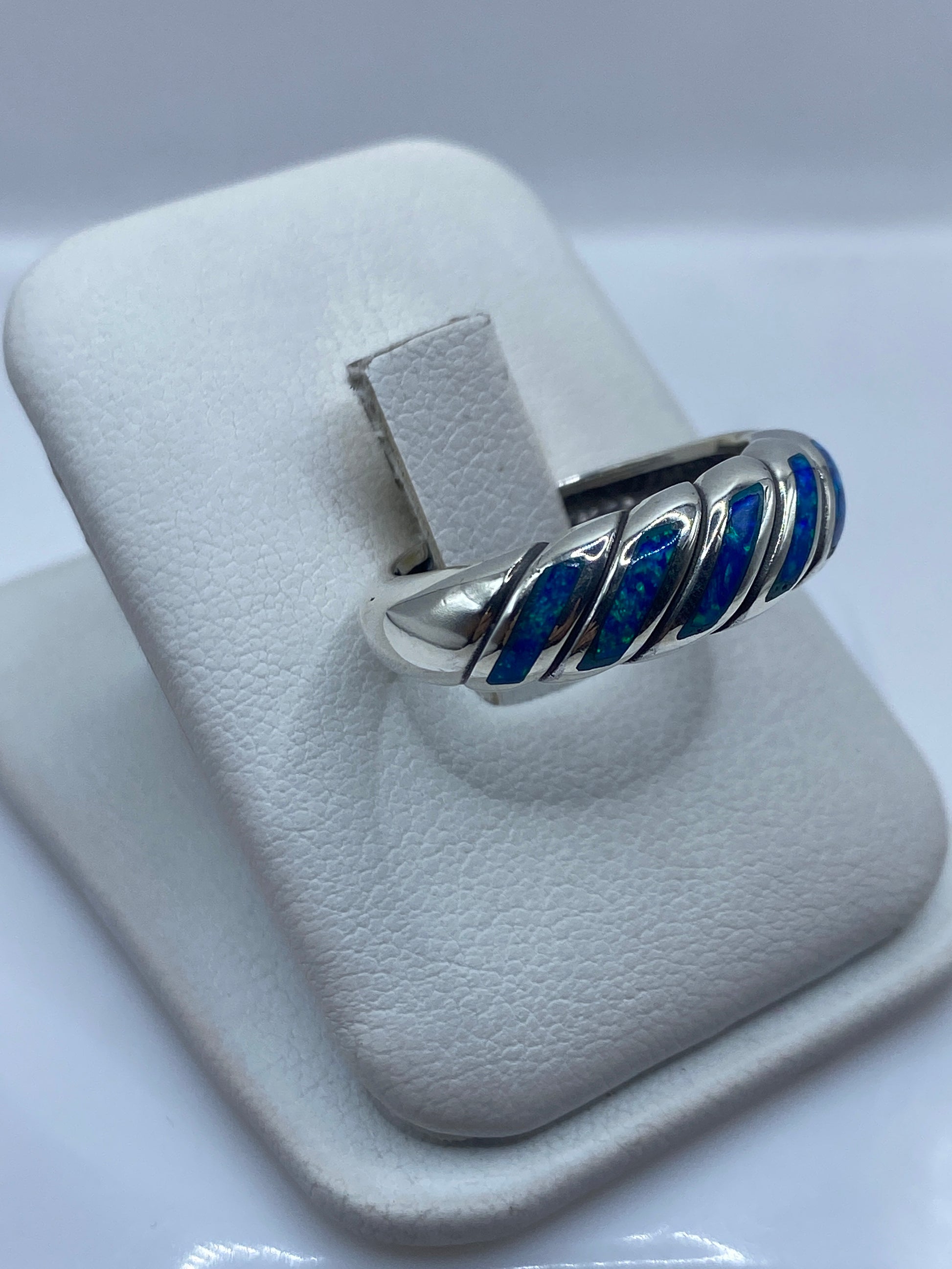 Anillo torsionado en plata con ópalo de fuego mostrando juego de luz azul-verde