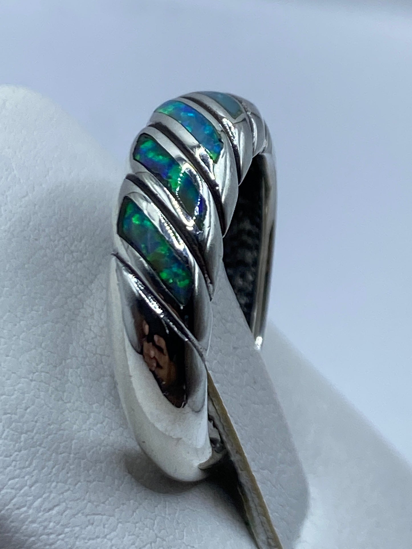 Anillo puesto en mano mostrando el brillo del ópalo y la suavidad de la rotación