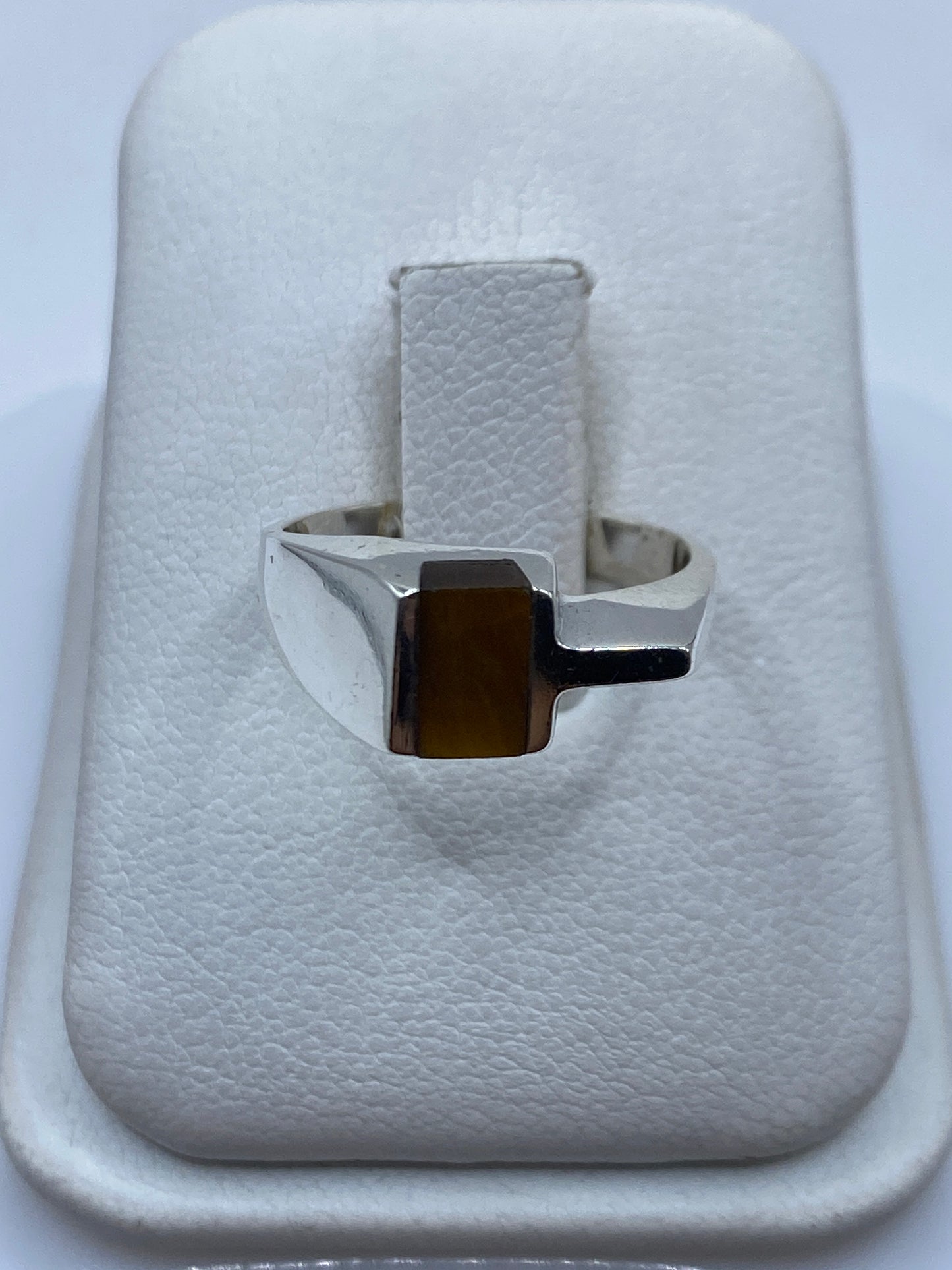 Anillo de plata con piedra café natural en la mano de una mujer
