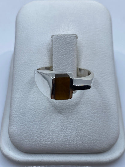 Anillo de plata con piedra café natural en la mano de una mujer