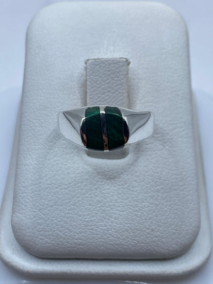 Anillo de plata con malaquita verde en banda geométrica, sobre cojín blanco